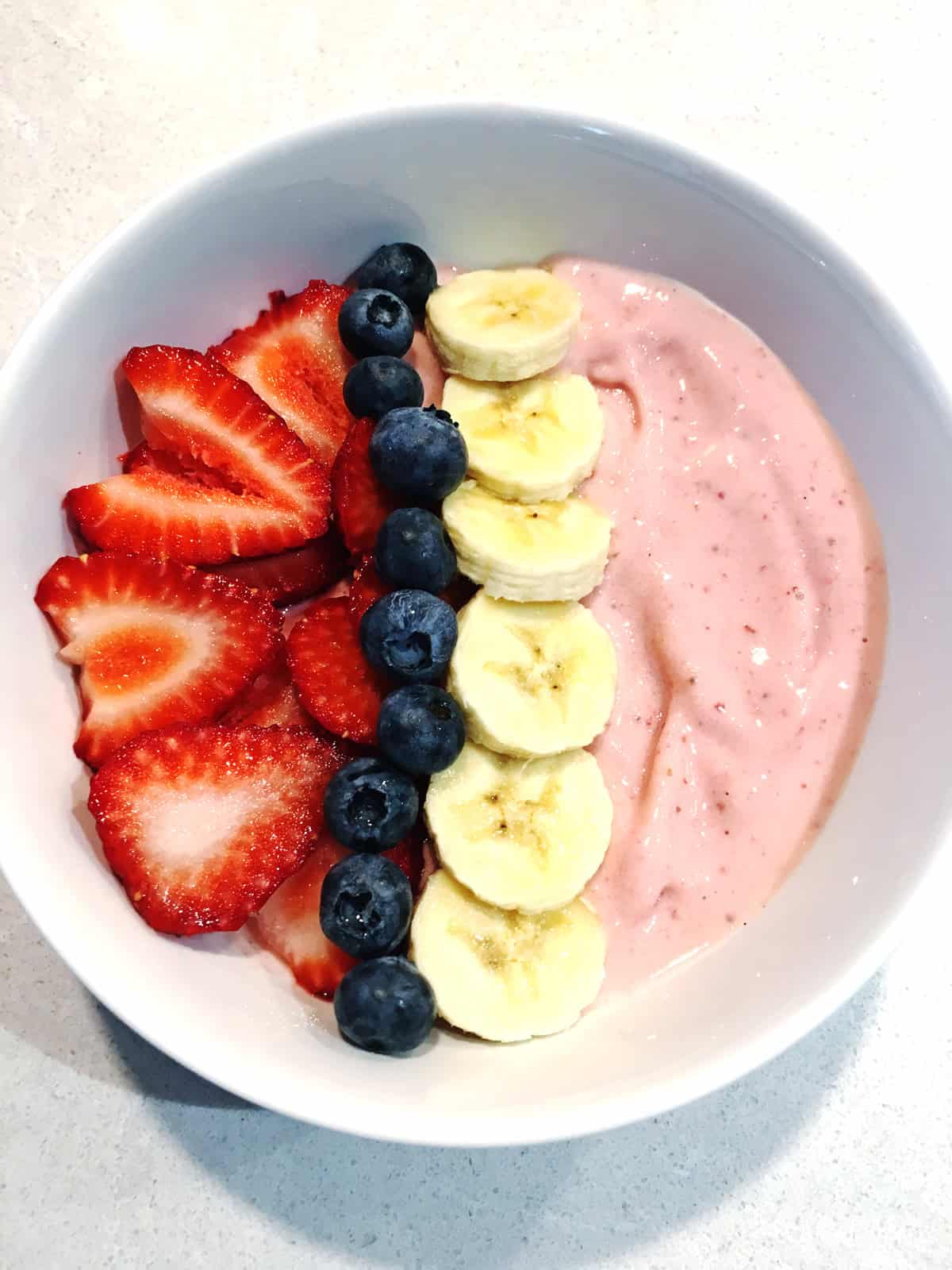 5-minute strawberry banana smoothie bowl in a white desert bowl atop a light grey marble countertop