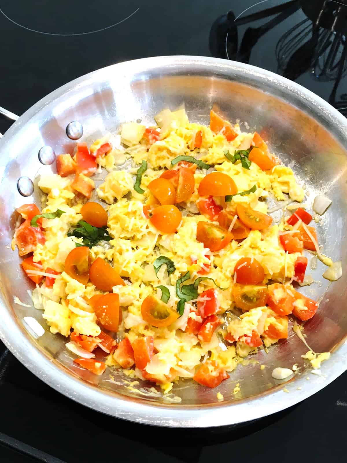 Parmesan scrambled eggs with veggies in a stainless steel skillet