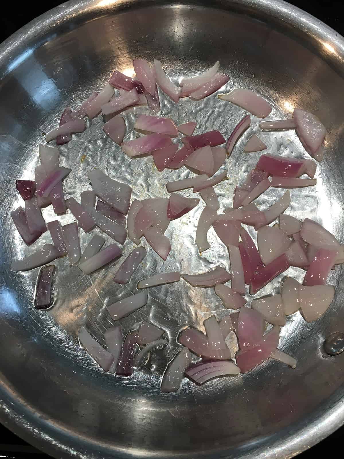 Red onions sauteing with coconut oil in a hot skillet