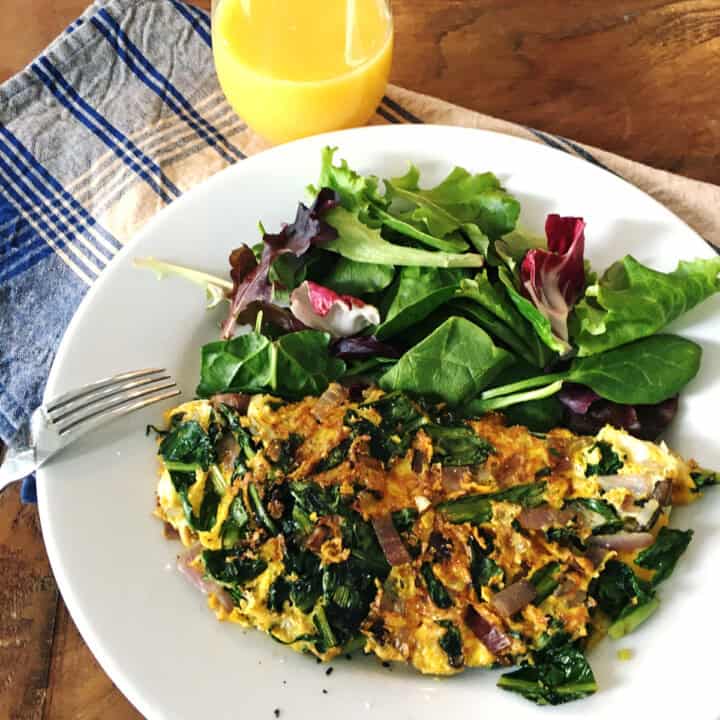 Dandelion greens omelette with mixed salad greens on a white plate