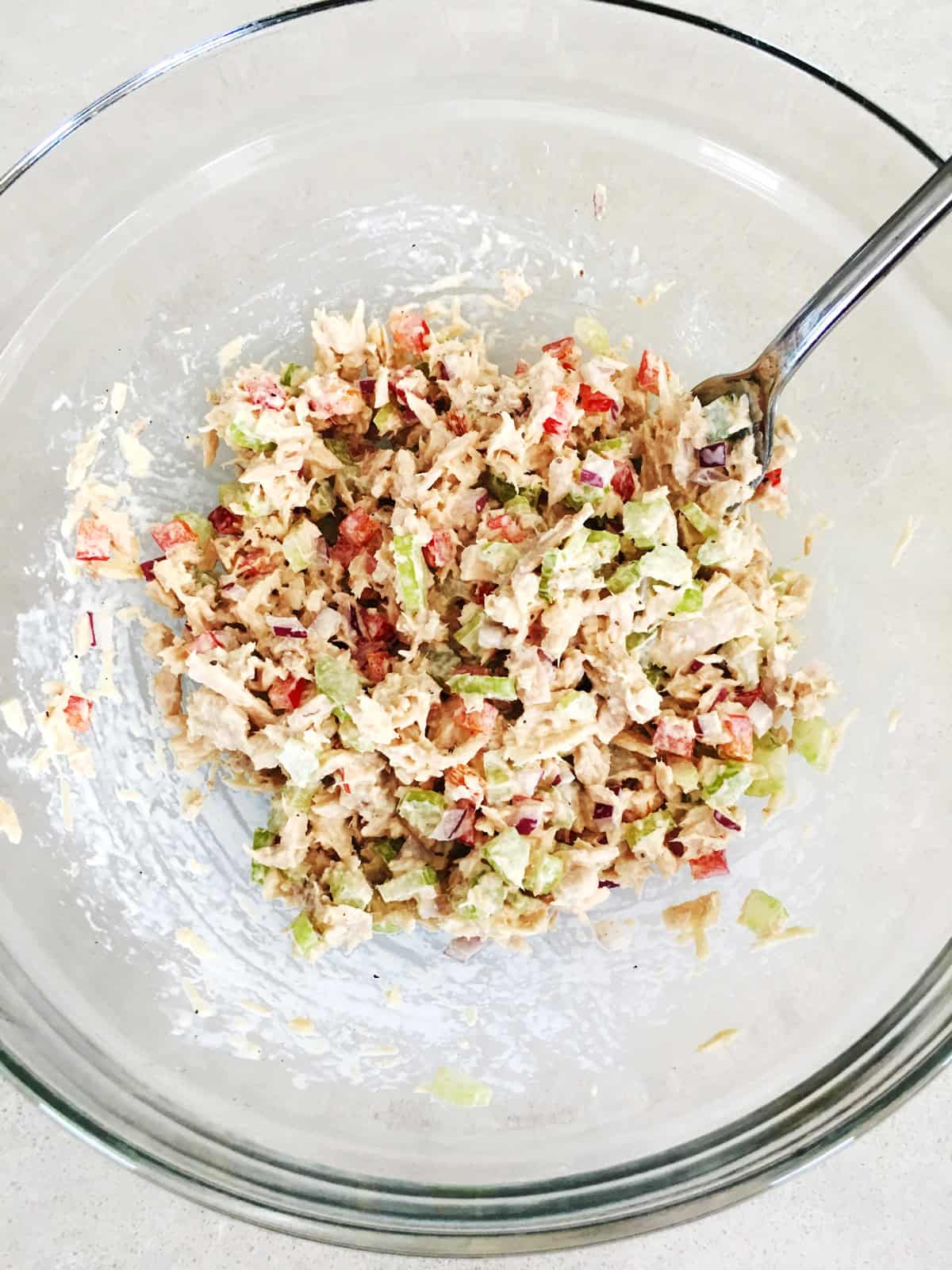 Freshly prepared tuna salad in a glass mixing bowl.