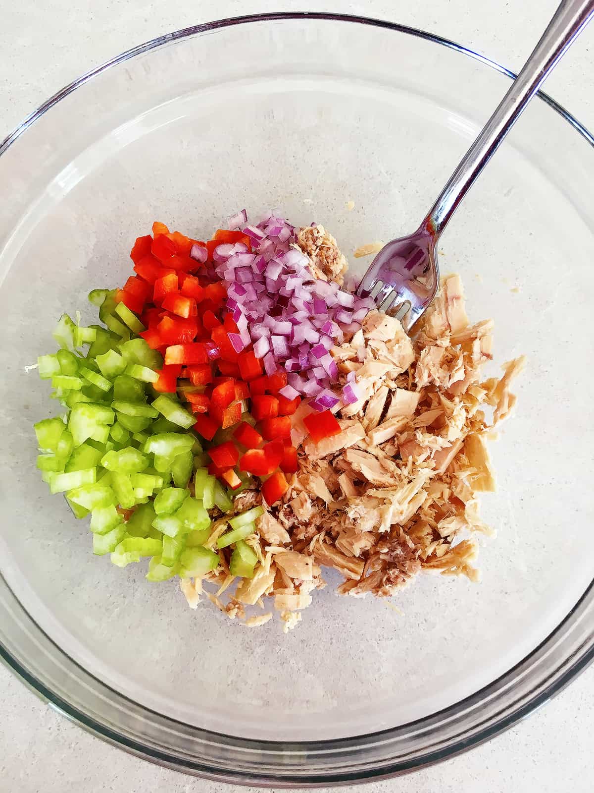Freshly chopped vegetables and tuna in a glass mixing bowl