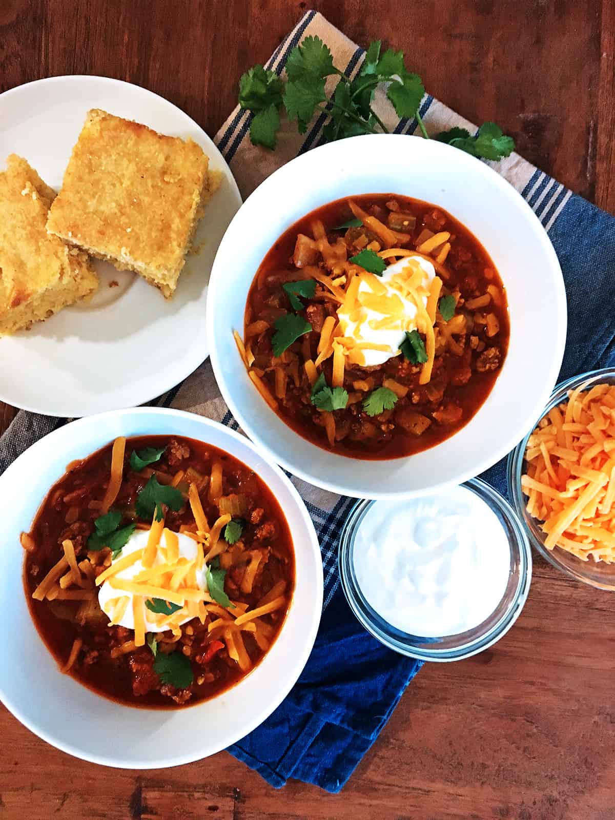 Quick and easy chili with a dollop of sour cream and shredded cheese in two white serving bowls.