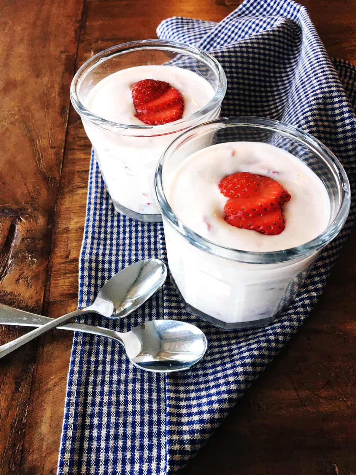 Homemade strawberry Instant Pot yogurt in two working glasses atop a blue and tan plaid napkin.