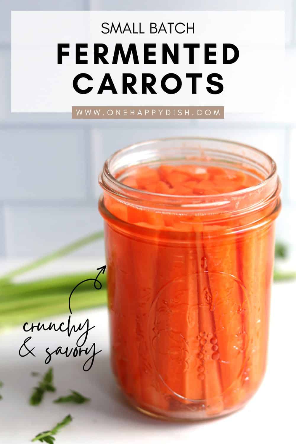 Fermented carrots in a Mason jar on a white marble countertop.