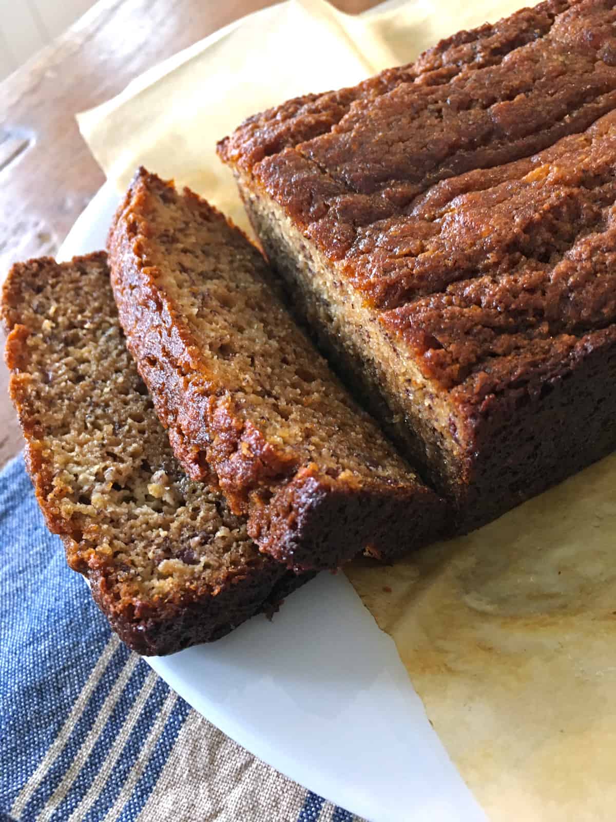 Gluten free banana bread atop parchment paper on a brown table.