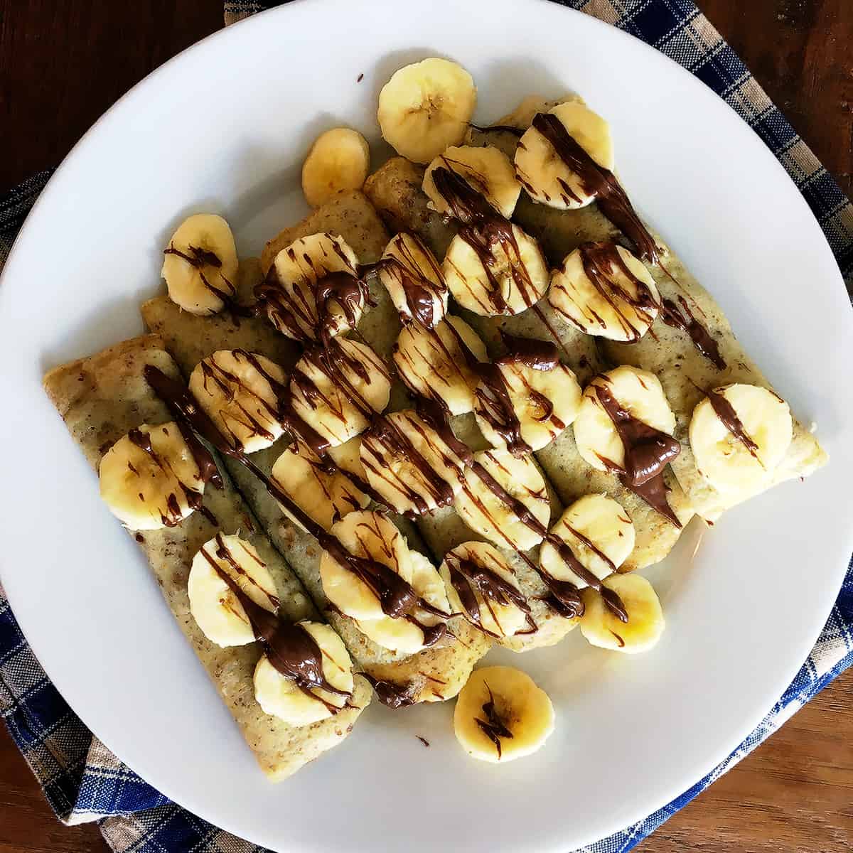 Banana Nutella crepes on a white plate.