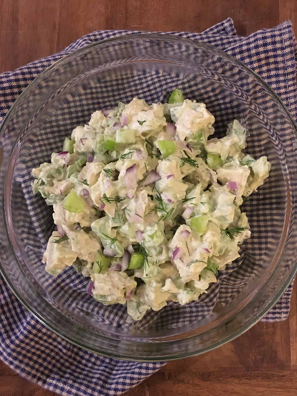 Chicken salad with avocado in a glass bowl on a brown table