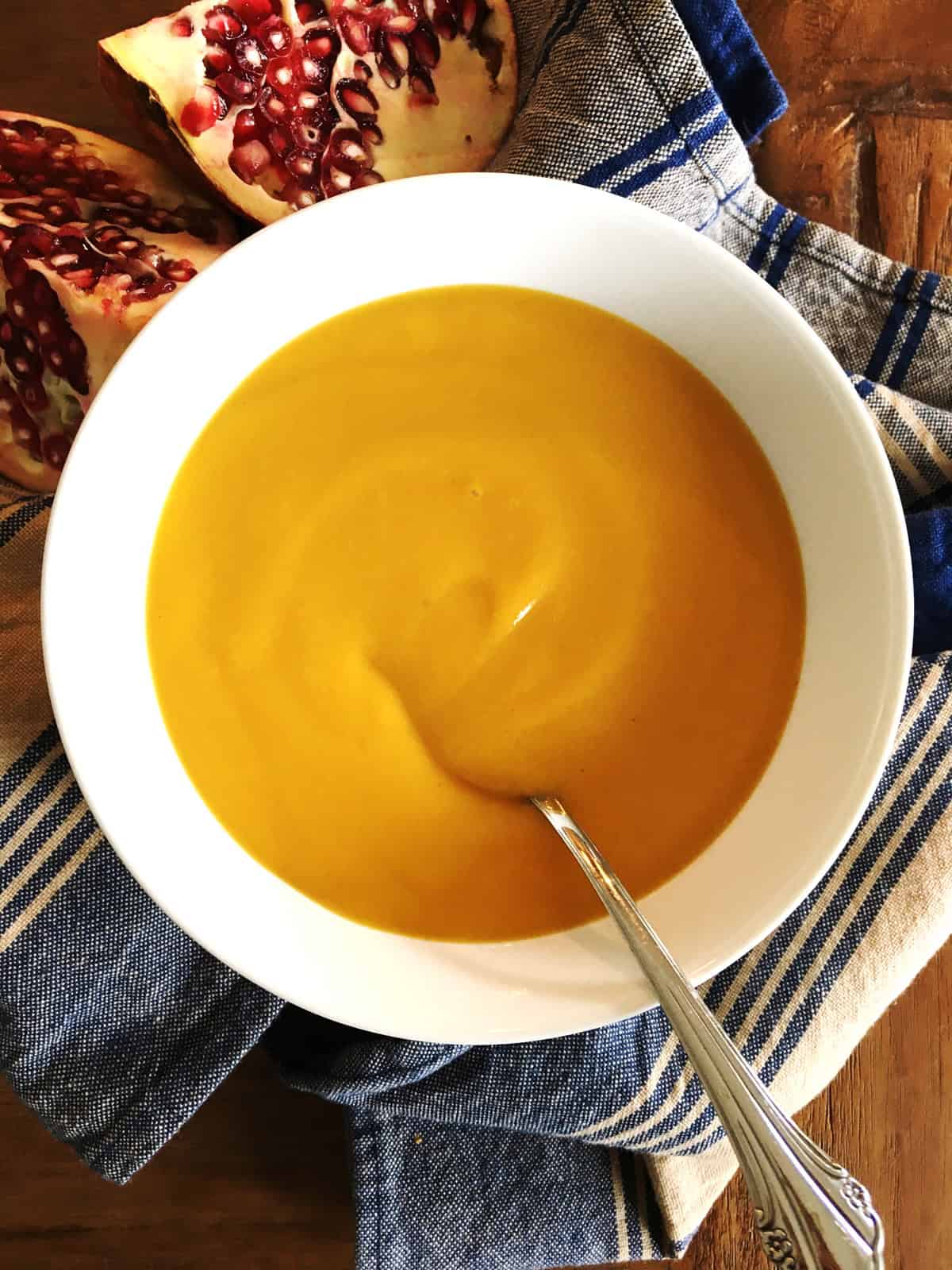 Roasted butternut squash soup in a white bowl with a silver spoon.