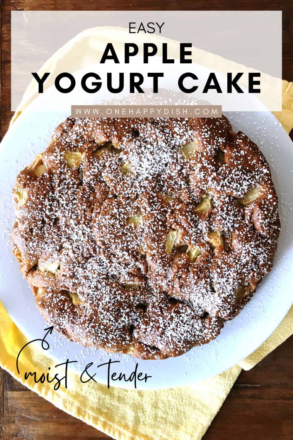 Apple yogurt cake dusted with powdered sugar on a white plate.