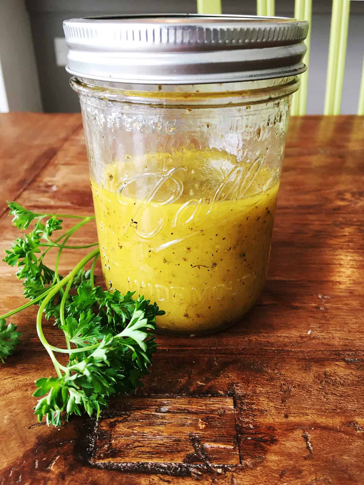 Apple cider vinaigrette dressing in a Mason jar on a brown wood table.