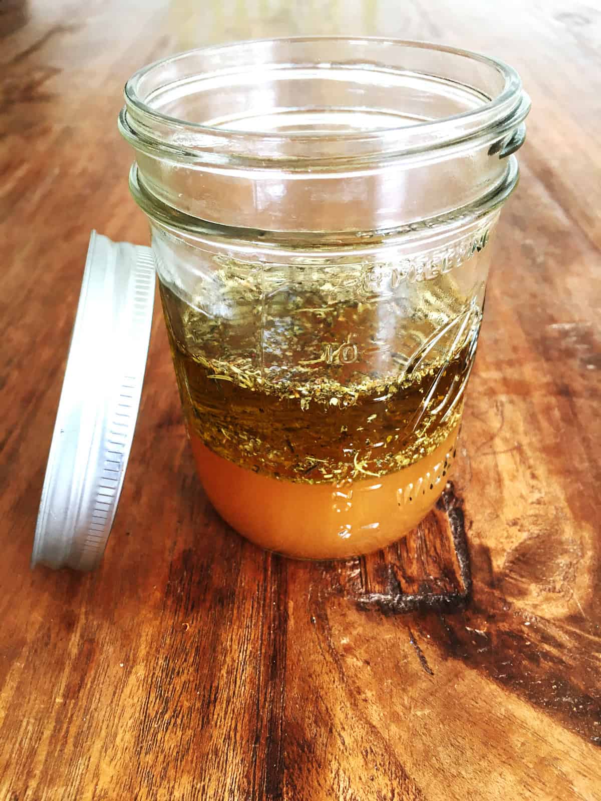 Vinegar, olive oil and Italian seasoning in a pint-sized Mason jar.