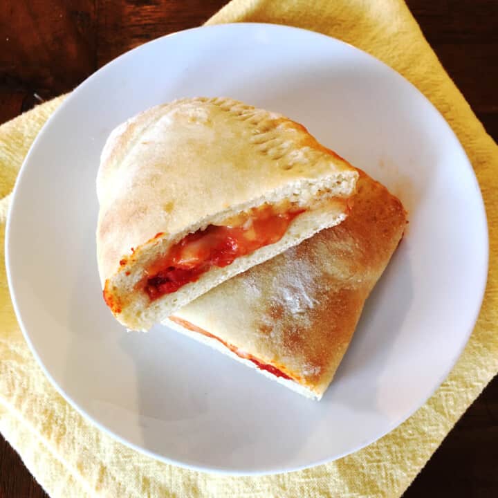 Cheese calzone sliced in half on a white plate.