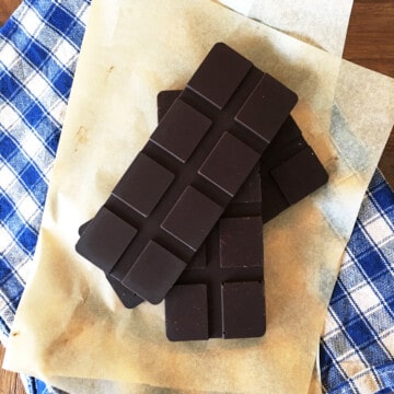 Three bars of homemade dark chocolate on parchment paper.