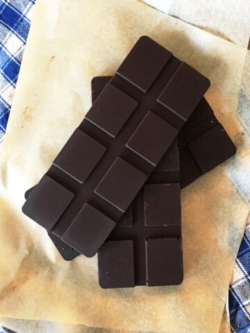 Three bars of homemade dark chocolate on parchment paper.