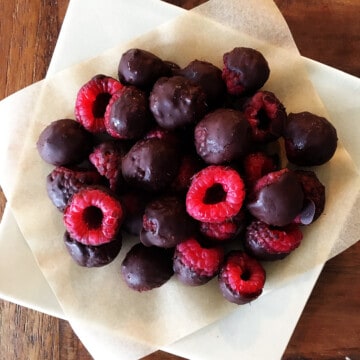 Chocolate covered raspberries on a ceramic square plate.