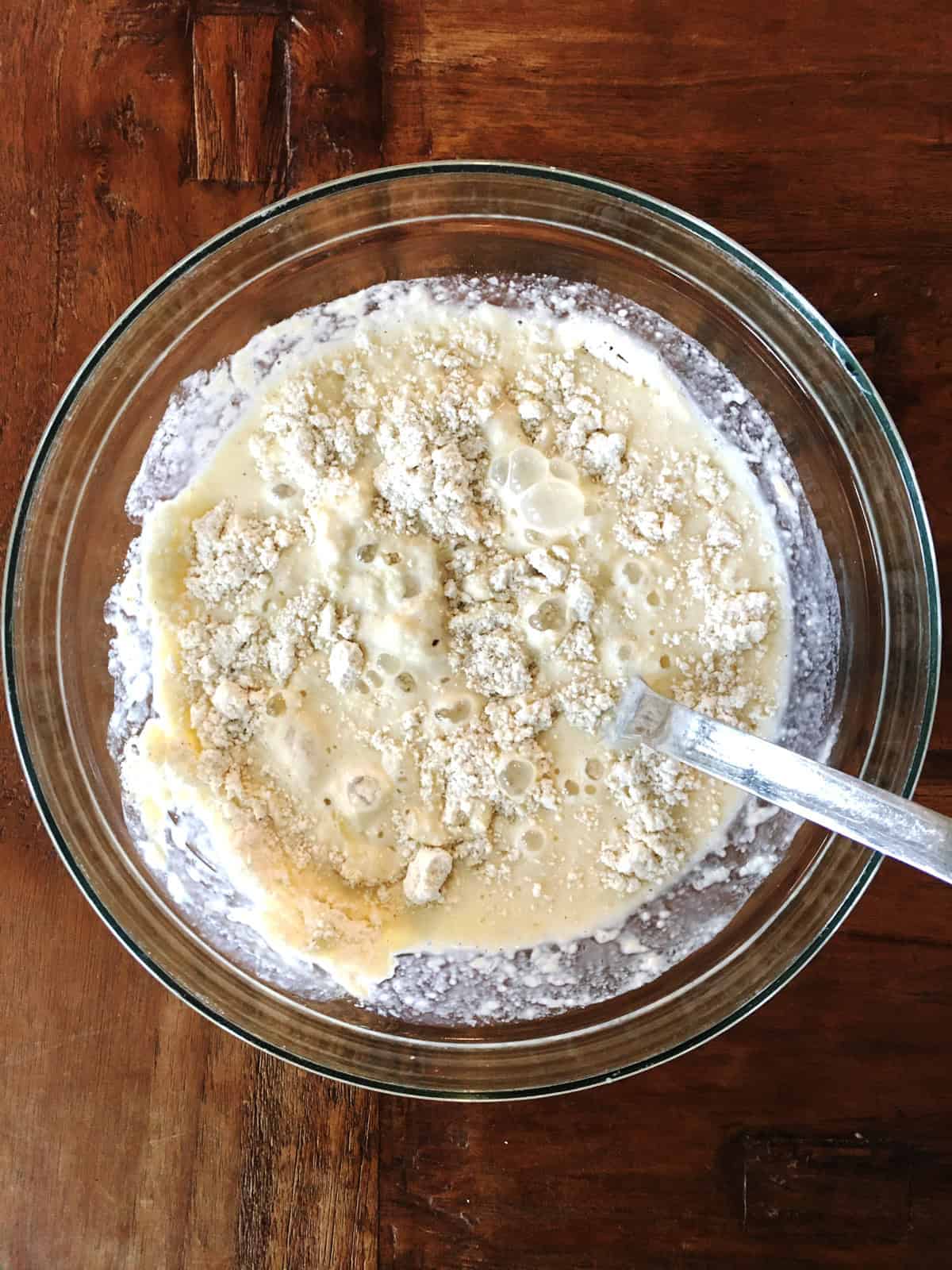 Mixing gluten free pancake batter in a glass mixing bowl with a stainless steel spoon