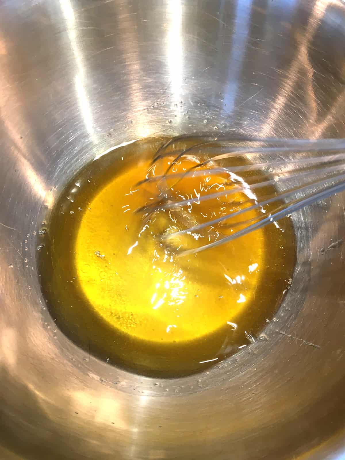 Melted cocoa butter and honey in a stainless steel bowl.