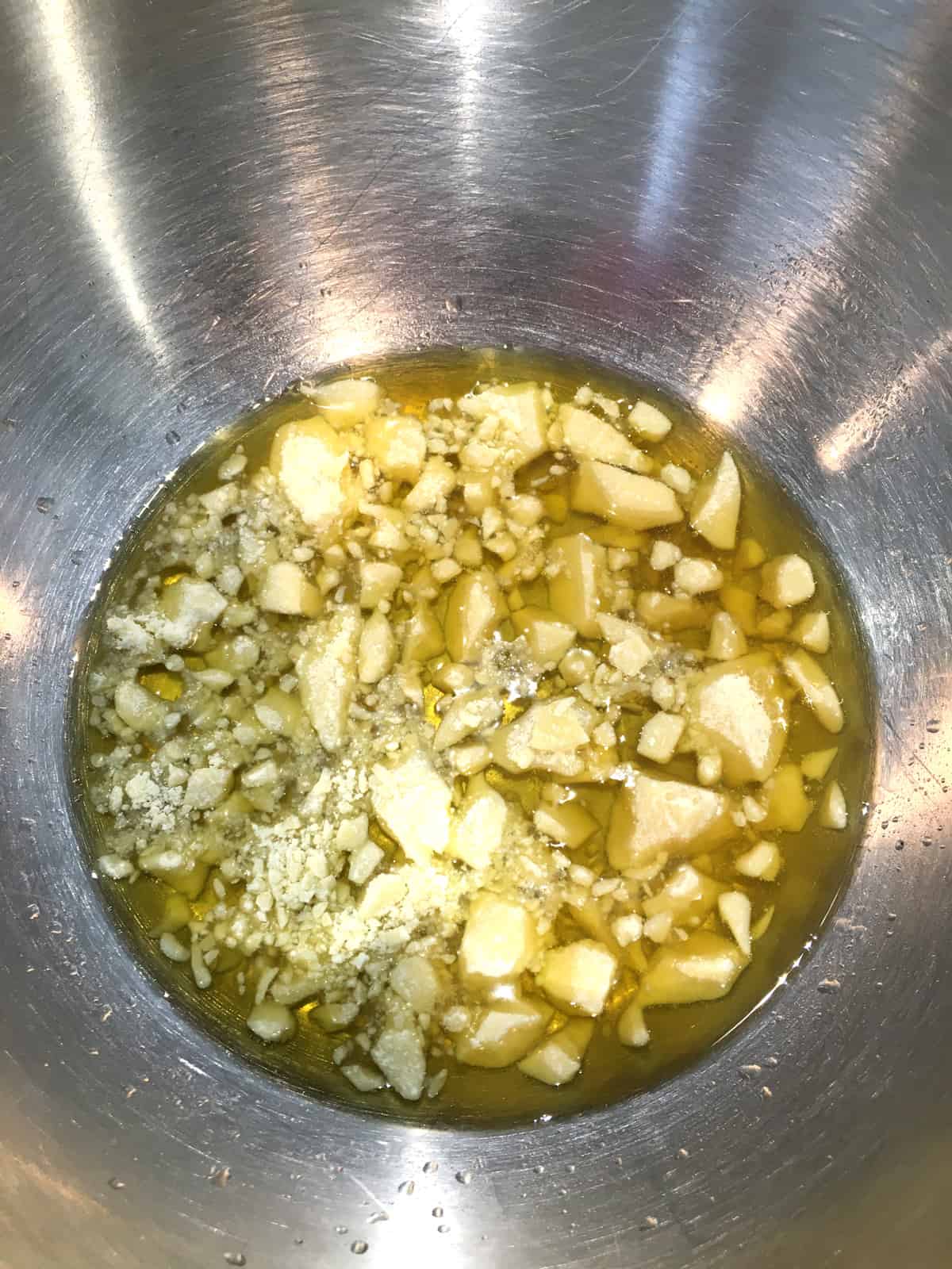 Cocoa butter melting in a stainless steel bowl.