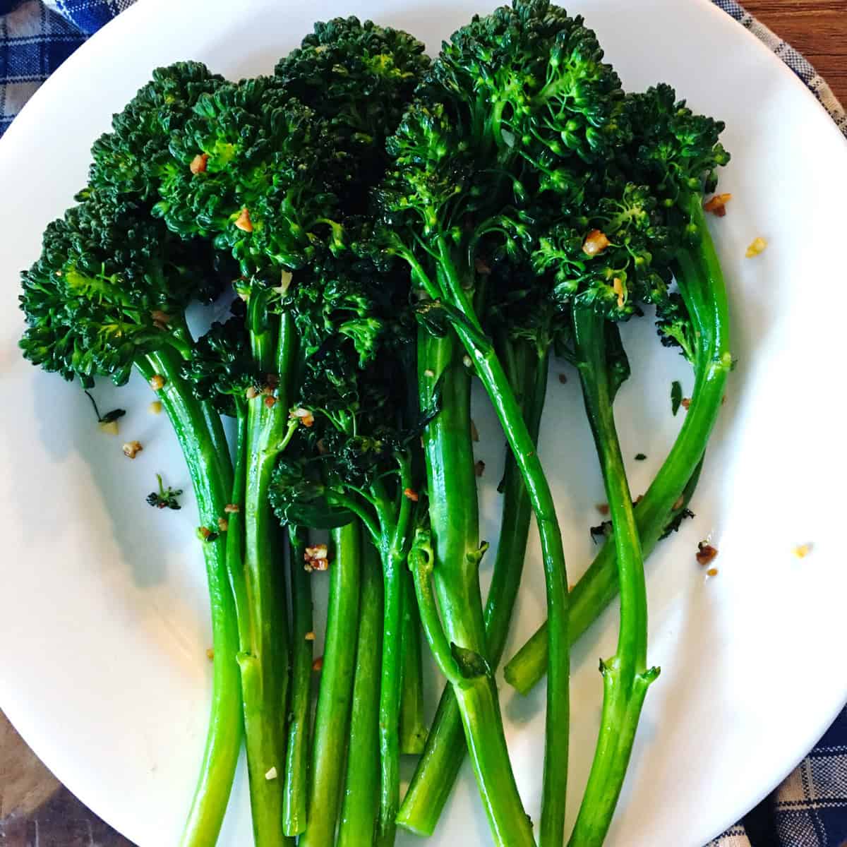 Sautéed broccolini with garlic on a white plate.