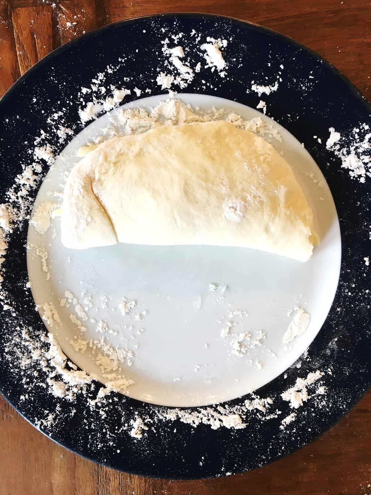 Calzone dough folded over the filings on a blue and white plate.