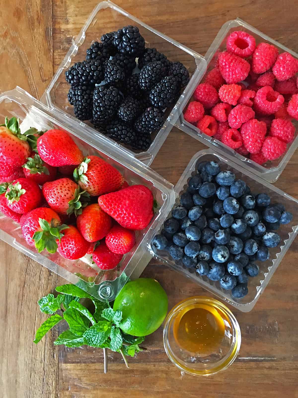 Fresh berry fruit salad ingredients on a brown wood table