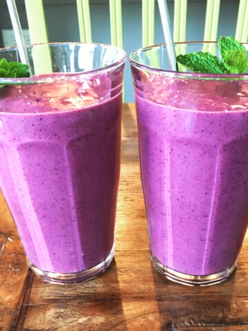 Two berry smoothies garnished with fresh mint.