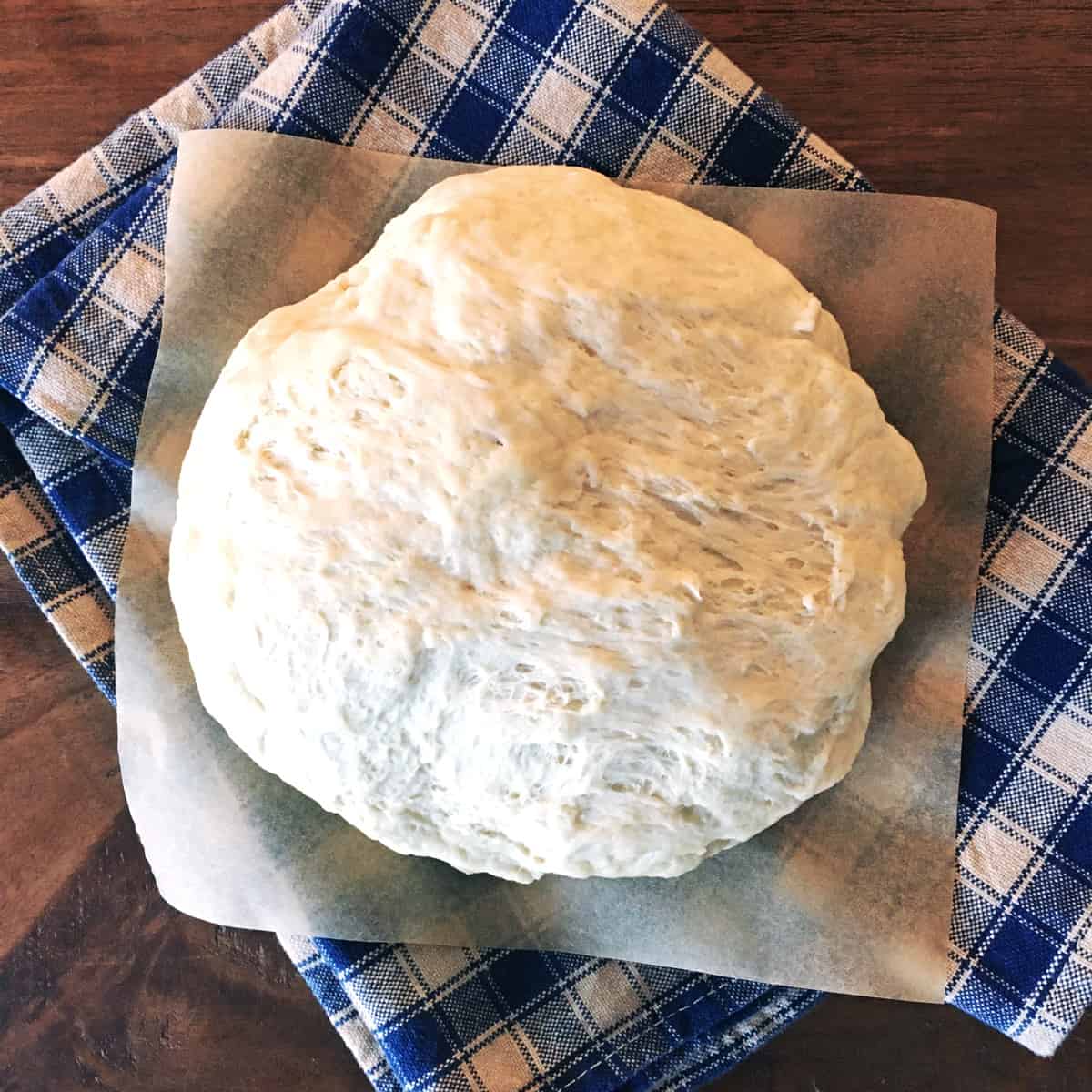 Homemade pizza dough on parchment paper.