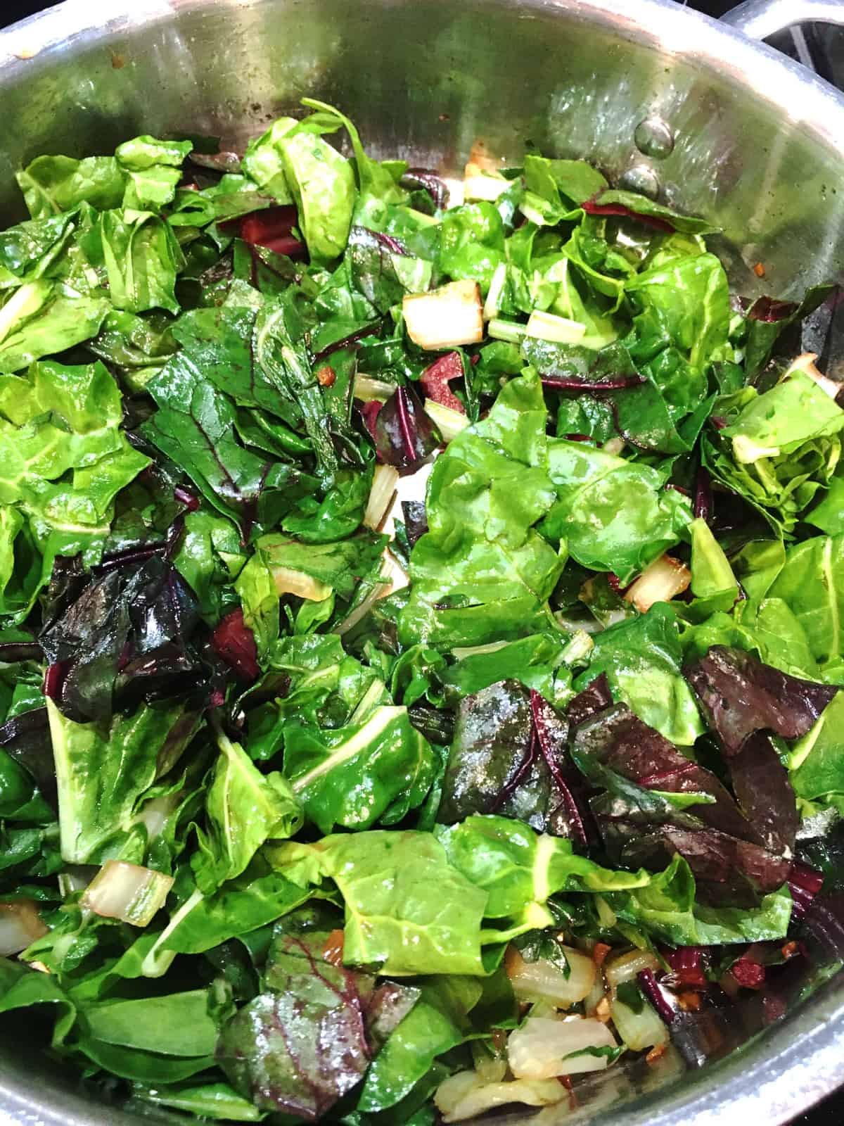 Swiss chard sautéing in a stainless steel skillet.