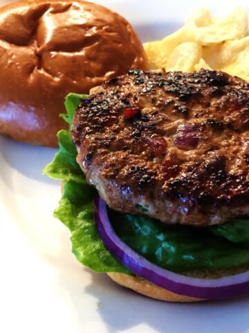 Turkey burger and potato chips on a white plate.