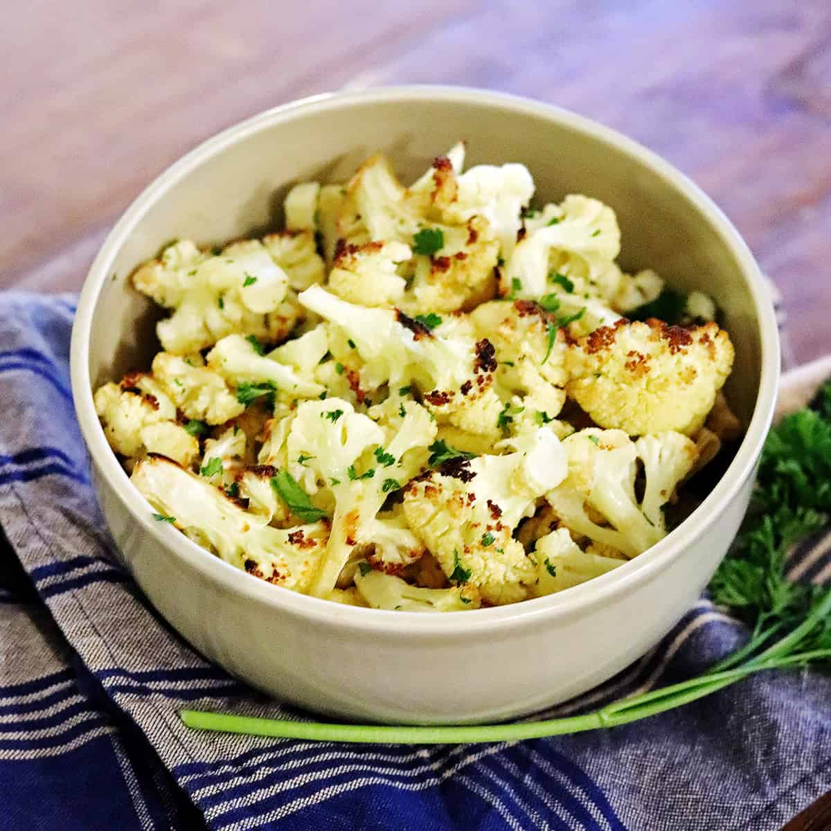 Roasted cauliflower in a tan ceramic serving bowl.