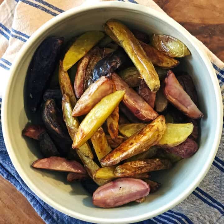 Roasted fingerling potatoes in a tan serving bowl.