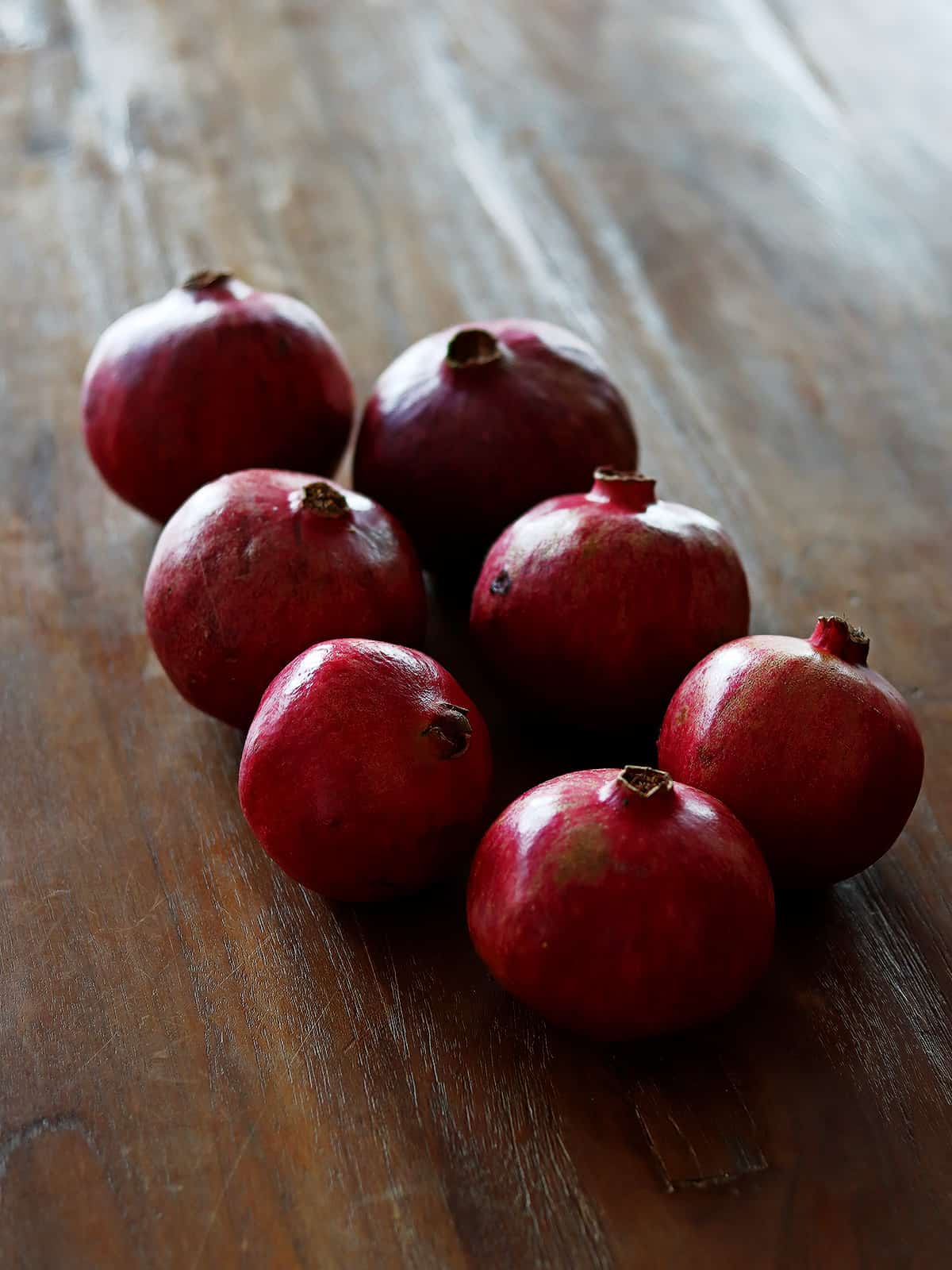 Group of pomegranates on a brown wood table.