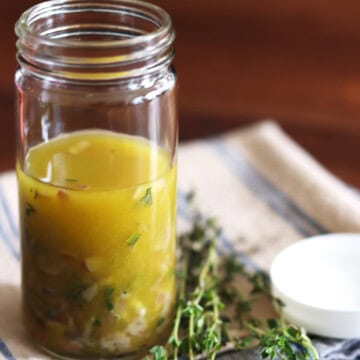 Homemade Niçoise salad dressing in a tall glass jar.