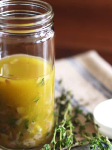 Homemade Niçoise salad dressing in a tall glass jar.