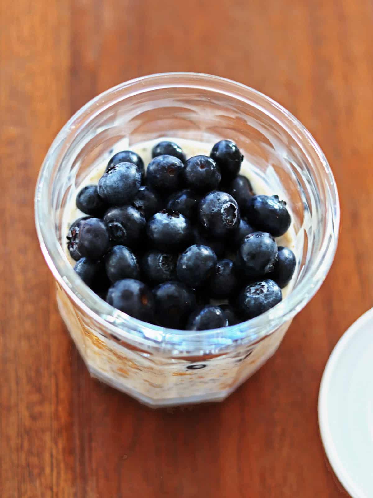 Overnight oats topped with fresh blueberries in a glass working jar.