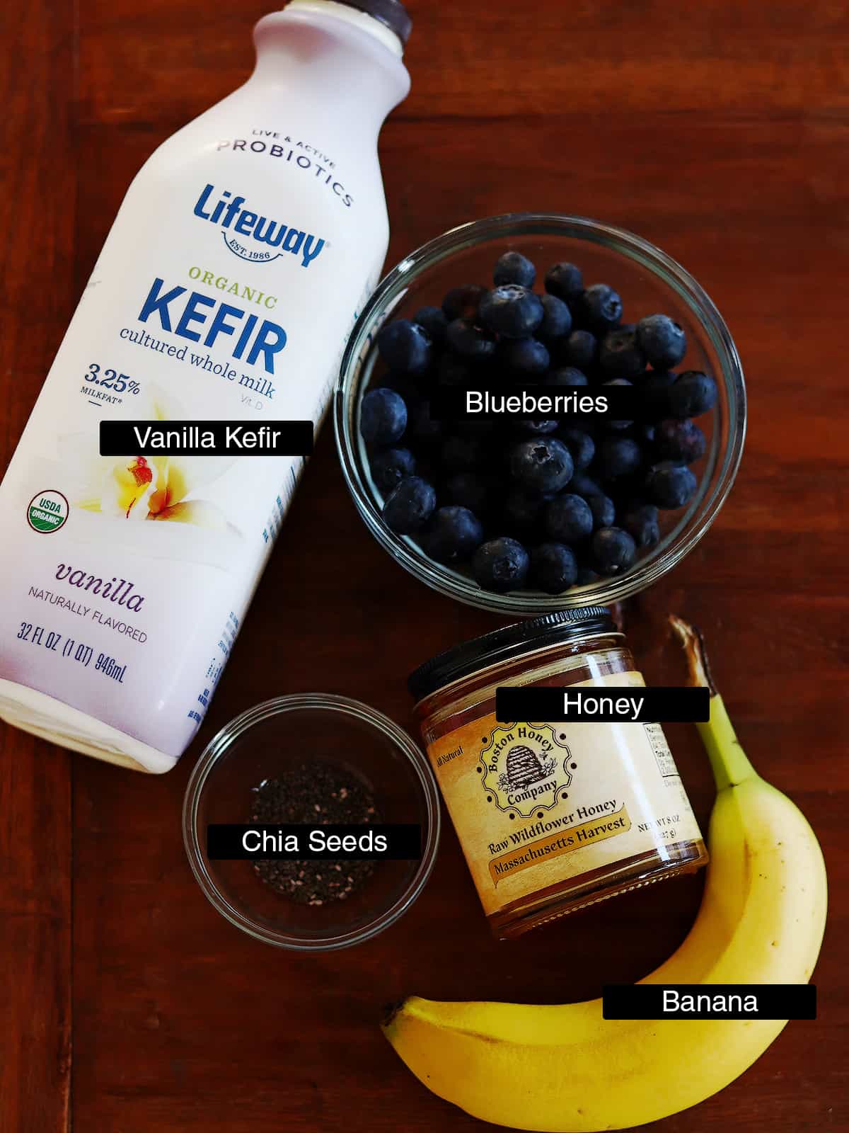 Blueberry kefir smoothie ingredients on a brown wood table.