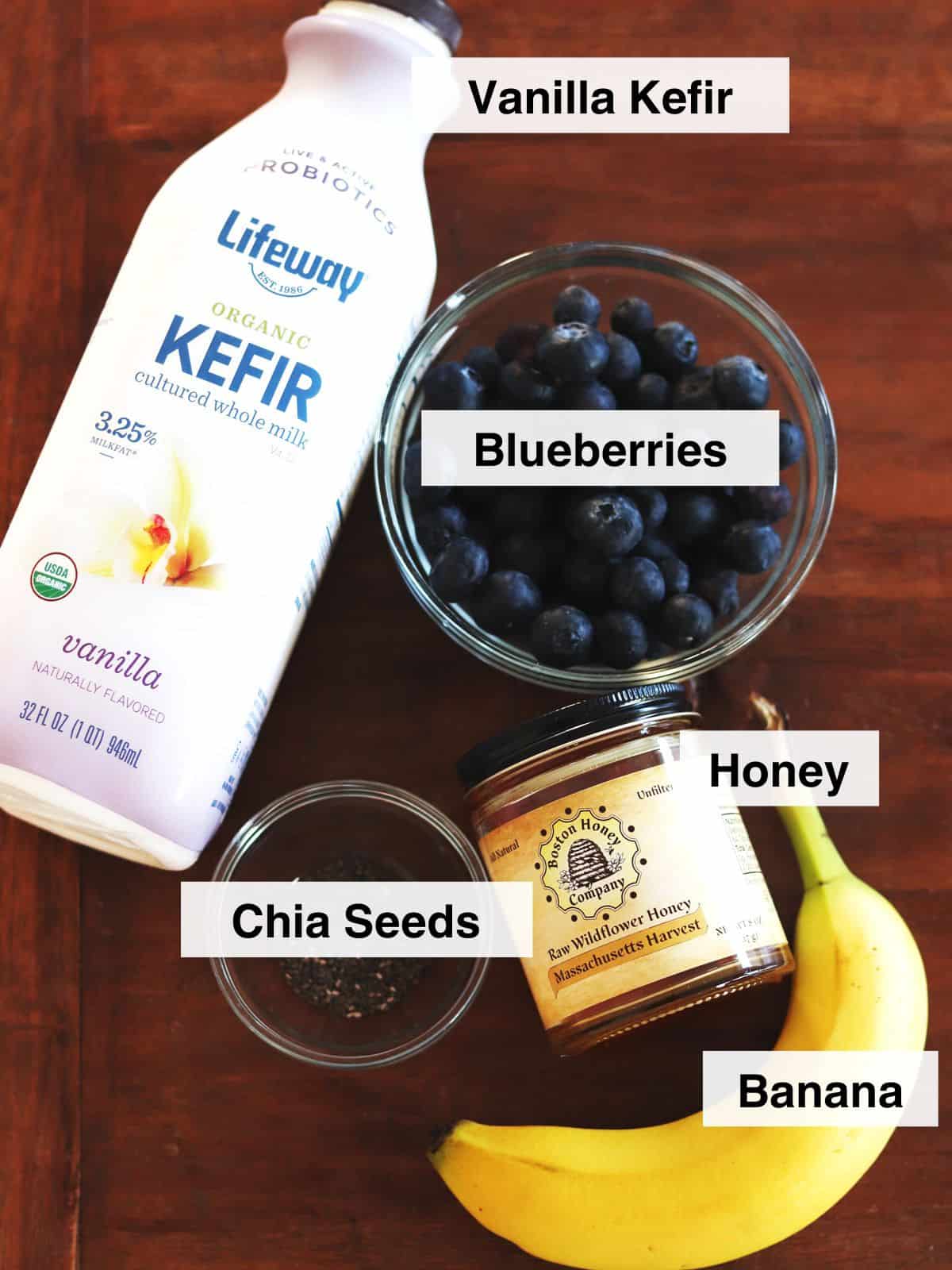 Blueberry kefir smoothie ingredients on a brown wood table.