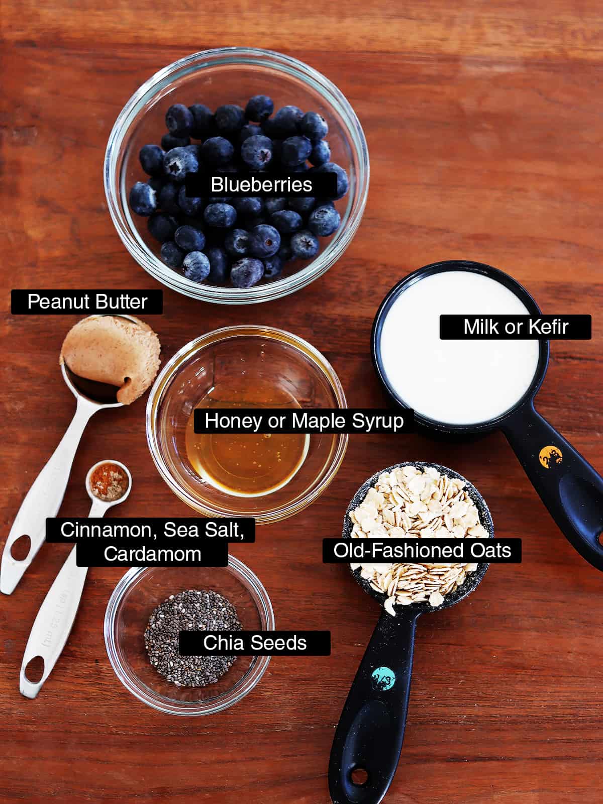 Ingredients for overnight oats with fresh blueberries on a brown wood table.