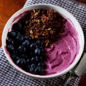 Black raspberry yogurt bowl topped with blueberries and granola.