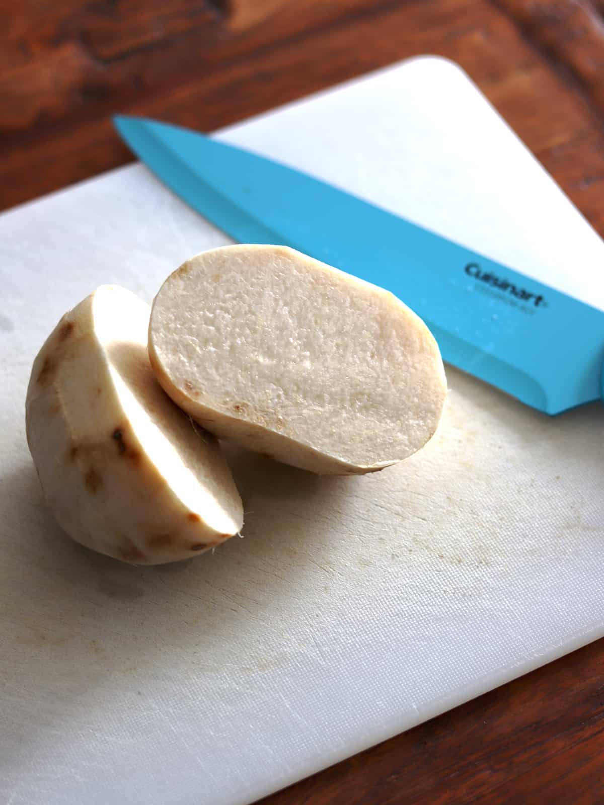 Halved jicama on a white cutting board.