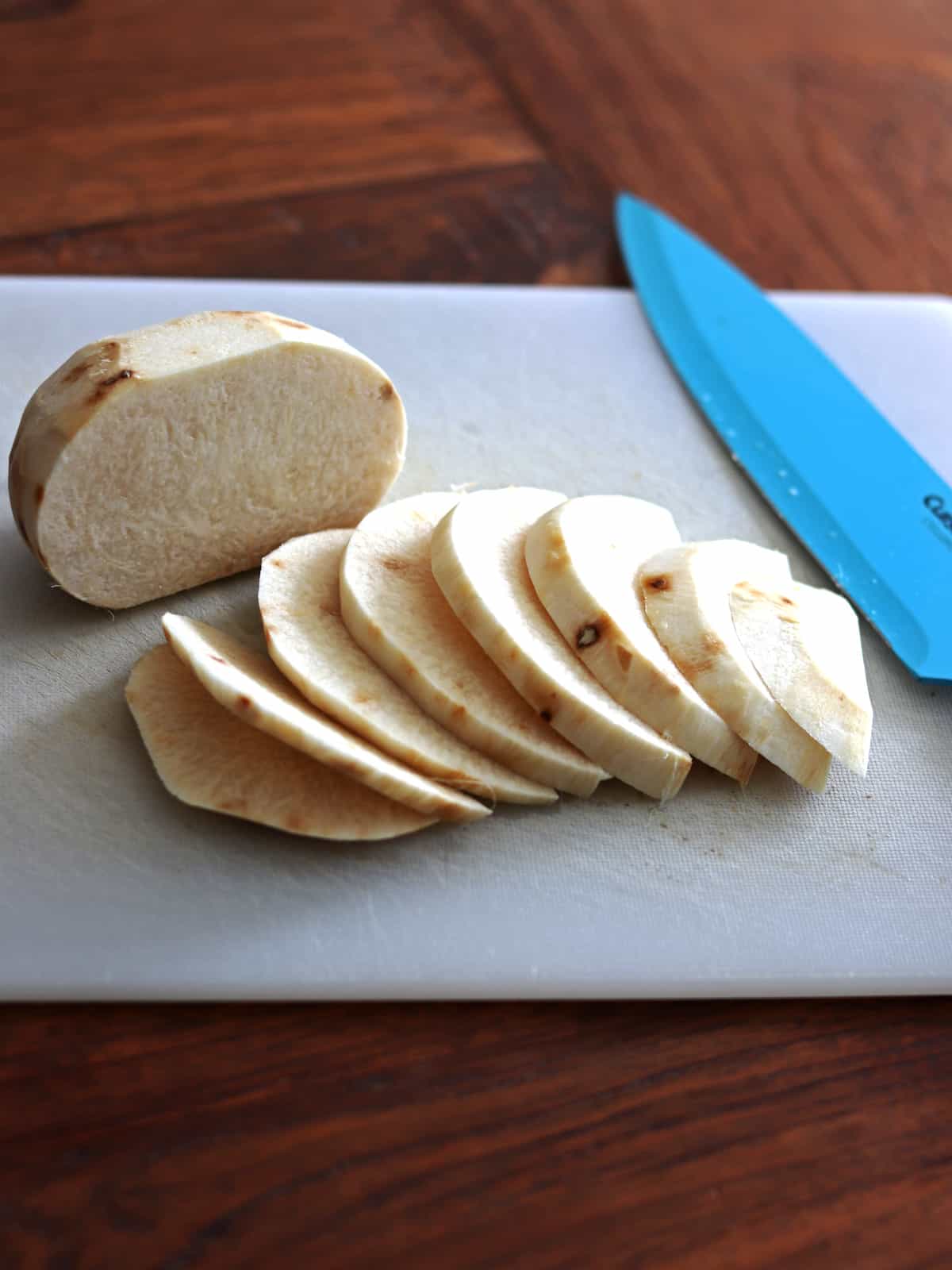 Sliced jicama on a white cutting board.