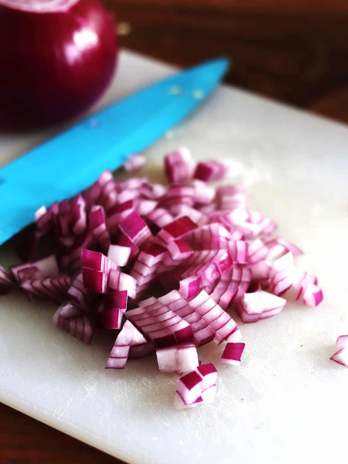 Diced red onion on a white cutting board.