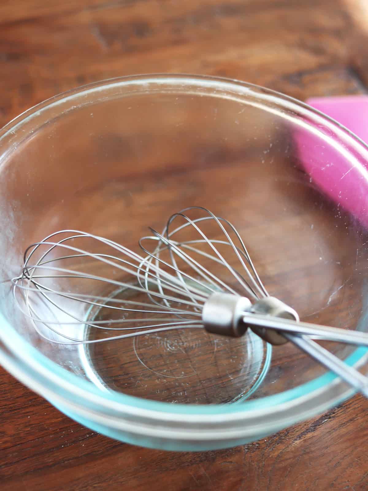 Chilled hand mixer whisk attachments in a cold glass mixing bowl.