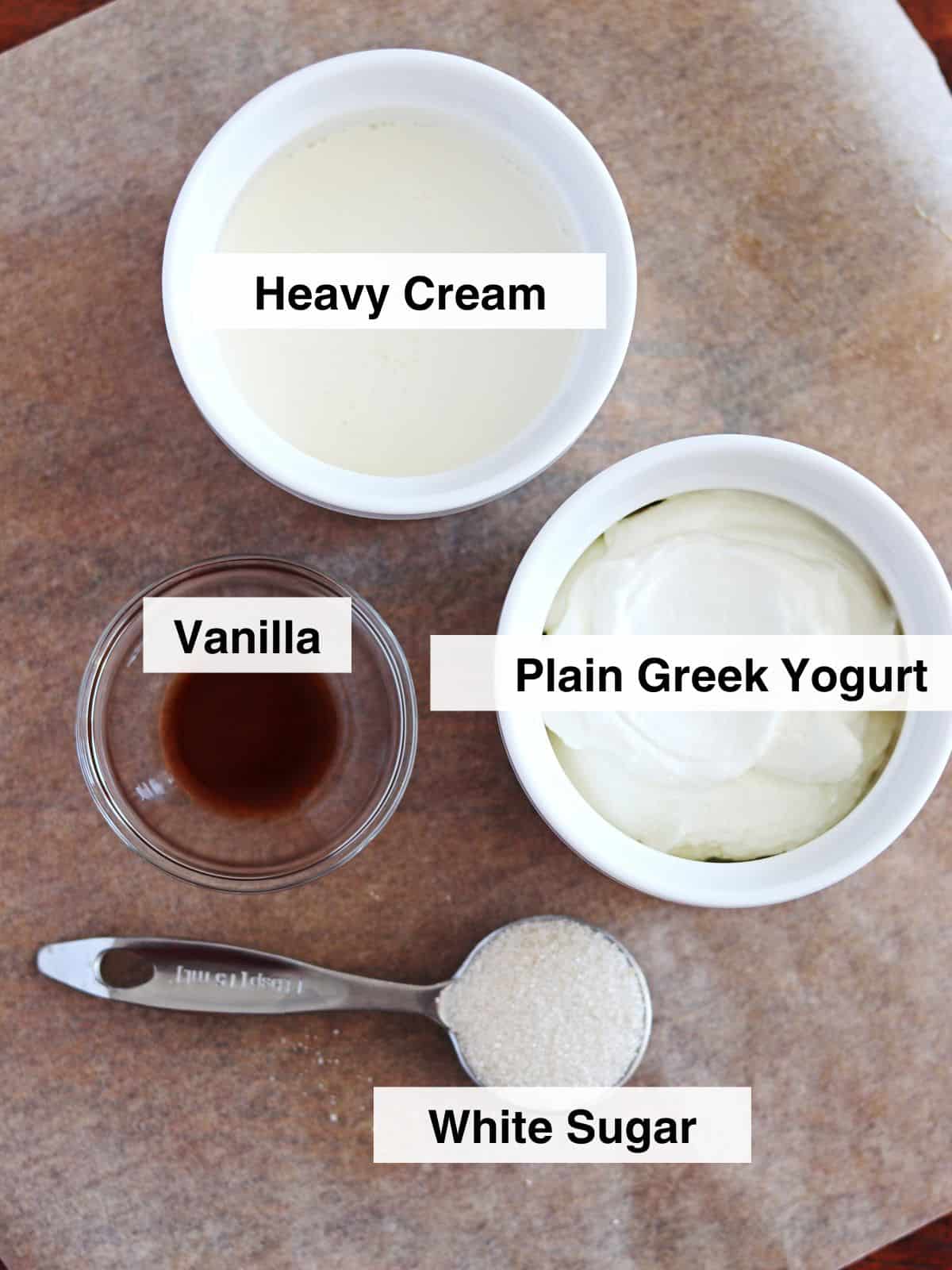 Ingredients for whipped Greek yogurt arranged on parchment paper.