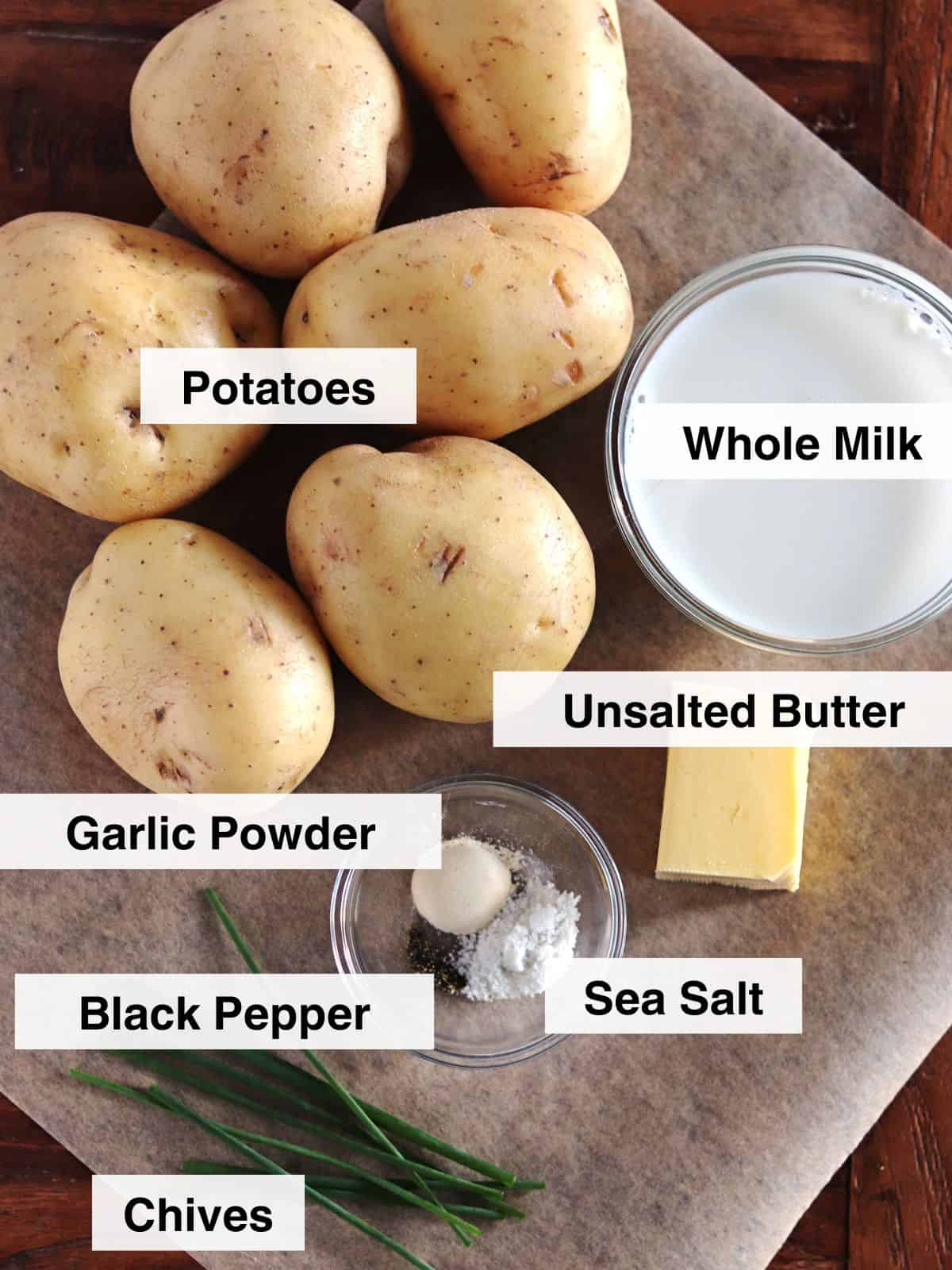 Mashed potato ingredients arranged on a parchment paper lined table.