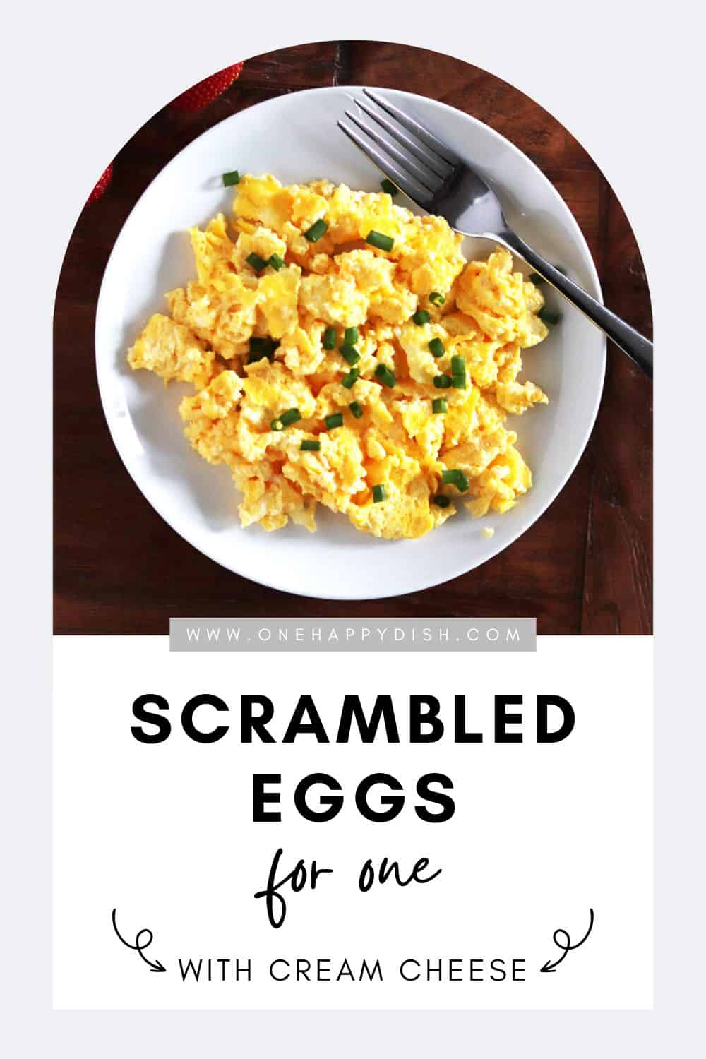 Scrambled eggs with cream cheese and chives on a white plate.
