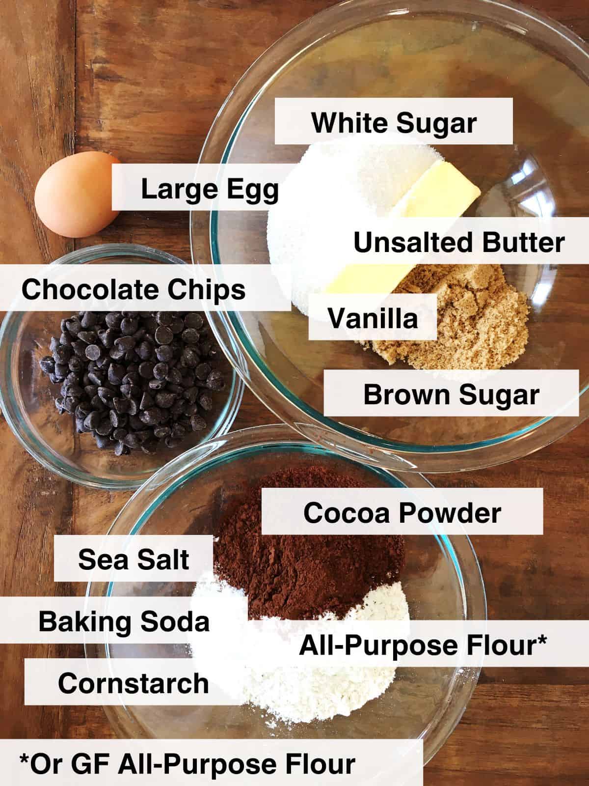 Ingredients for chewy double chocolate chip cookies arranged on a brown wood table.