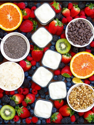 Yogurt charcuterie board with individual yogurt cups, fruit and toppings.