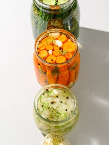 Homemade pickles, fermented carrots, sauerkraut and fermented garlic in glass jars.